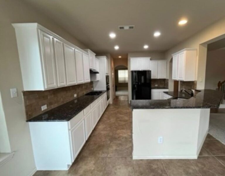 Bright remodeled kitchen with white cabinets, dark countertops, and a spacious island for everyday use